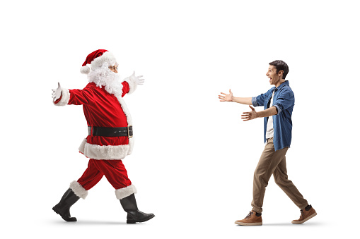 Full length profile shot of santa claus walking with arms wide open and meeting a young man isolated on white background