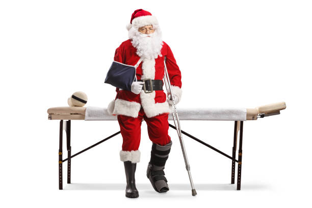 père noël triste avec une jambe et un bras blessés assis sur une table passe-partout - christmas crutch holiday christmas decoration photos et images de collection