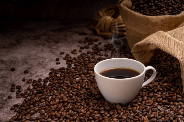 istock Hot coffee in a white coffee cup and many coffee beans 1738117444