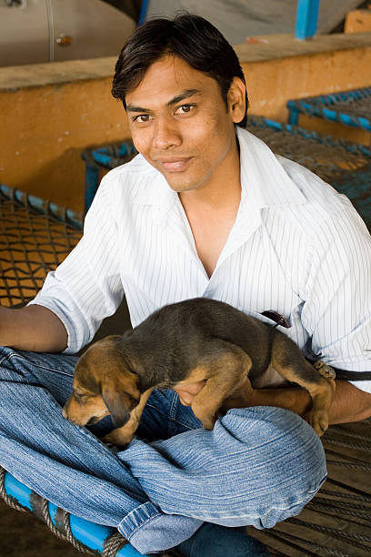 Indian youth playing with a puppy while waiting for his breakfast to come in a roadside Dhaba (a small resataurant) in India