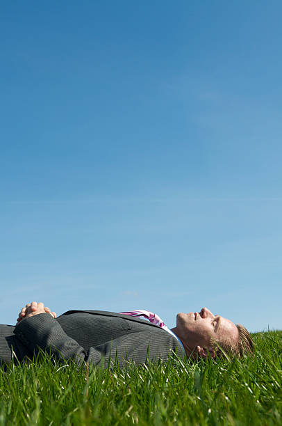 istock Businessman Lying in Green Grass Meadow Eyes Closed Blue Sky 173813208