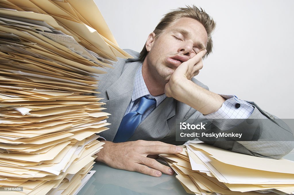 Businessman Office Worker Filing Asleep at the Job on Desk Office worker falls asleep amid a pile of file folders Boredom Stock Photo