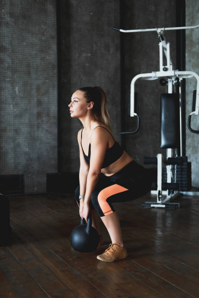 Young fitness woman doing swing exercise with a kettlebell as a part of a fitness workout stock photo