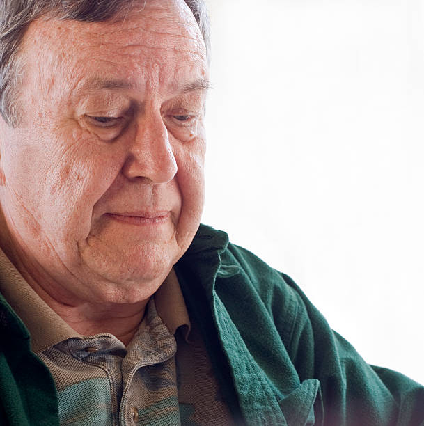 Senior man without glasses looking down stock photo