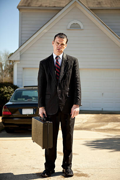 soaked businessman Soaked and wet businessman in his driveway holding his suitcase. soaked suit stock pictures, royalty-free photos & images