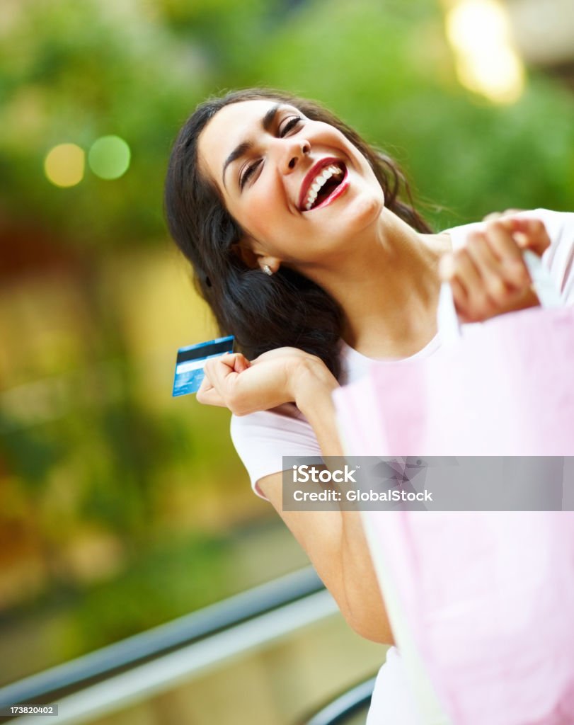 Animado Jovem mulher segurando o cartão de crédito e carregando sacos de compras - Foto de stock de 20 Anos royalty-free