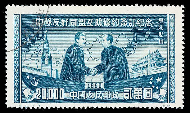 "A 1950 Chinese postage stamp with an illustration of Mao Zedong and Joseph Stalin shaking hands. A map of Eurasia, Spasskaya Tower (the Kremlin), and the Forbidden Palace are in the background. DSLR with macro lens; no sharpening."