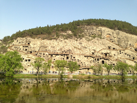 The Longmen Grottoes, located on bothsides of the Yi River to the south of the ancient capital of Luoyang, Henan province, comprise more than 2,300 caves and niches carved into the steep limestone cliffs over a 1km long stretch. These contain almost 110,000 Buddhist stone statues, more than 60 stupas and 2,800 inscriptions carved on steles. The grottoes and niches of Longmen contain the largest and most impressive collection of Chinese art of the late Northern Wei and Tang Dynasties (316-907). These works, entirely devoted to the Buddhist religion, represent the high point of Chinese stone carving. Here is the Longmen Mountain where the Longmen Grottoes were located, seen from the other bank of Yi River.
