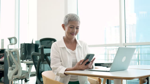 Senior woman using smartphone in a modern office
