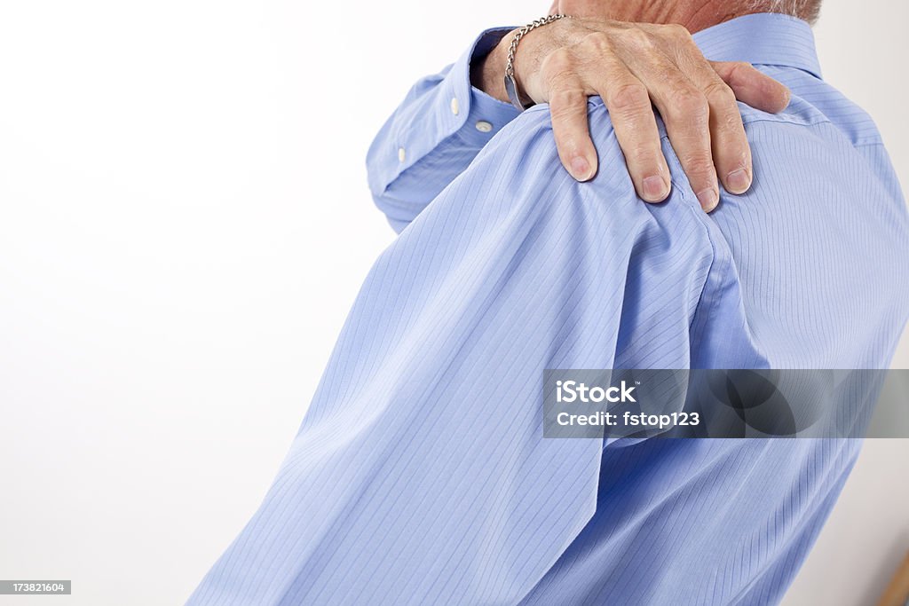 Senior man with hands rubbing shoulders and neck in pain Senior man wearing medical alert bracelet is rubbing his painful shoulder.    60-64 Years Stock Photo