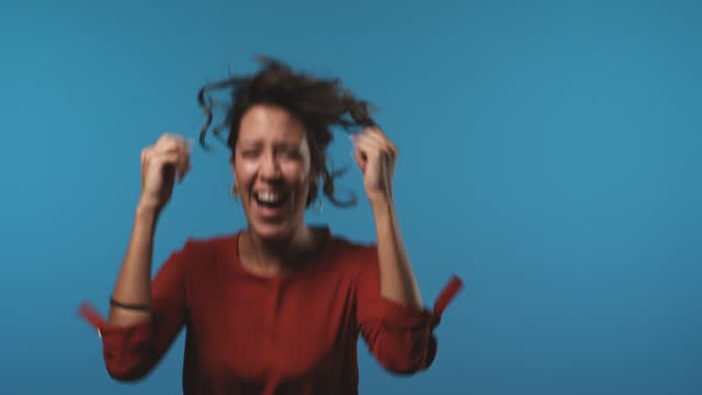 Cheerful young woman looking at camera and jumping with excitement when receiving good news
