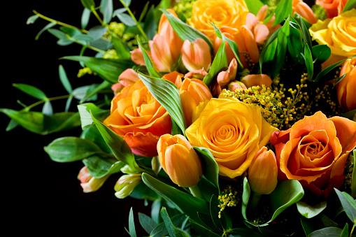 A closeup of an orange daisies and roses bouquet on a wooden background