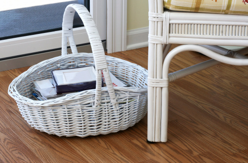 White wicker basket and chair on hardwood floor.