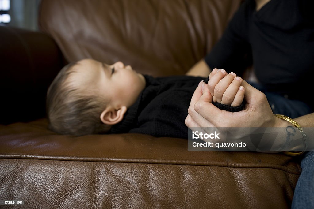 Привлекательная Латиноамериканская Baby мальчик спит на диване, мать держит руки - Стоковые фото Внимательно смотреть роялти-фри