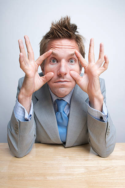 istock Tired Businessman Office Worker Propping His Eyes Open at Desk 173825163