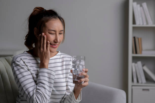istock Woman feels toothache while drinking cold water sitting on sofa at home. 1738269709