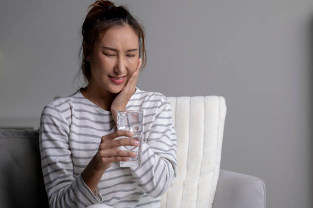 istock Woman feels toothache while drinking cold water sitting on sofa at home. 1738269713