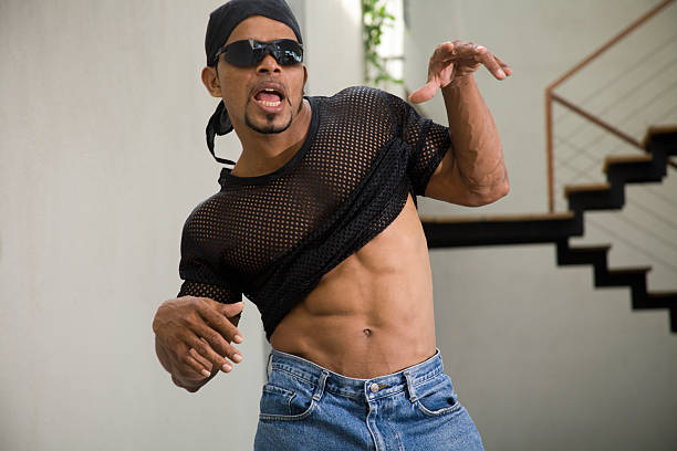 cool dude in shades dances to the beat "A cool dude in dark shades, blue jeans and see through mesh teeshirts pulls his shirt up to reveal his muscular abs while he dances to the music. A 400 ASA image unsharpened from Eos 5D, Ample copy space, Why not find what you want in" do rag stock pictures, royalty-free photos & images