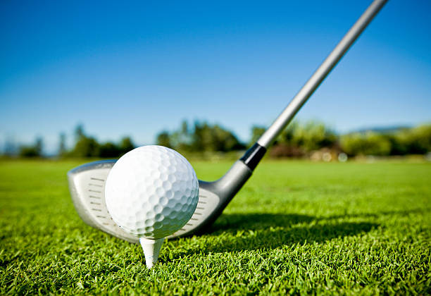 golf ball on tee and golf club on golf course - golfclub stockfoto's en -beelden