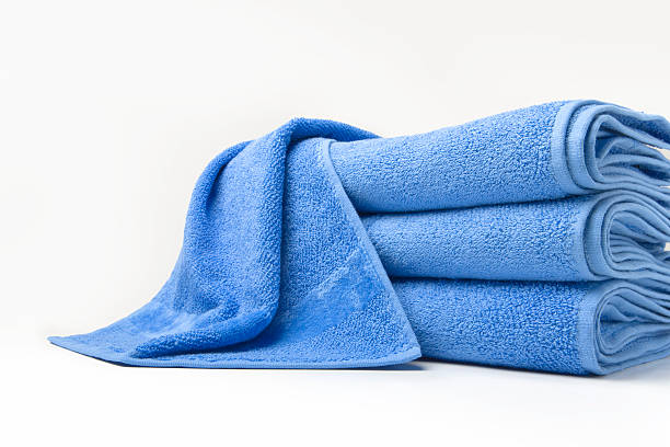 Stack of folded blue cotton towels with one draped on top
