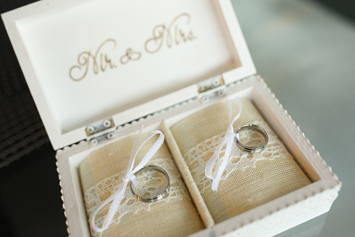 Open wood jewelry box with Mr and Mrs text containing wedding rings