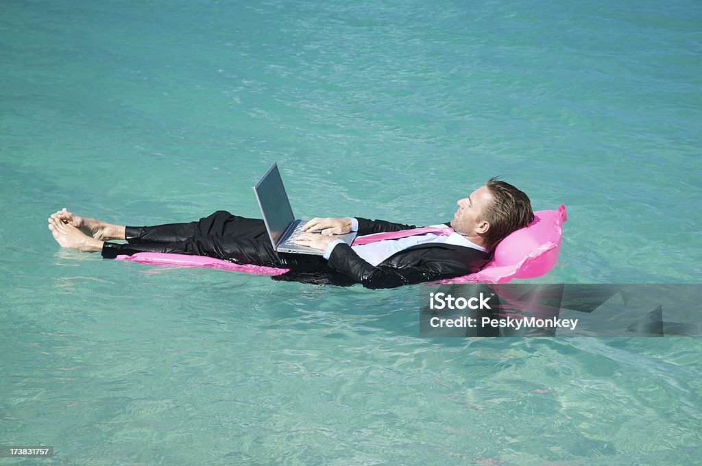 Homme d'affaires décontractée travaillant de dactylographie sur Lilo flottant dans l'eau tropicale - Photo de Humour libre de droits