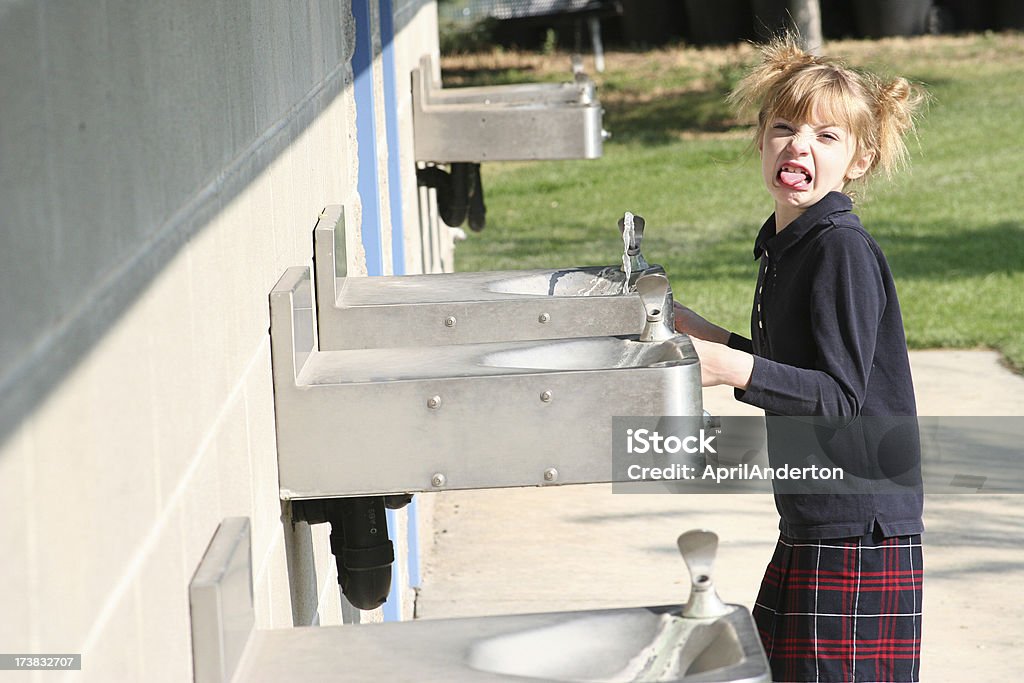 Bambino in Uniforme scolastica bere acqua nella Fontana bad - Foto stock royalty-free di Puzzolente