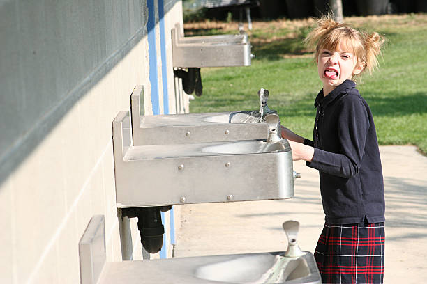 A girl getting a refreshing drink from a drinking fountain.