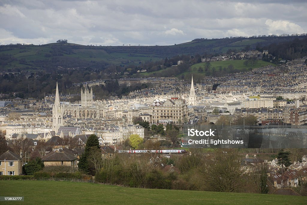 Bath city centre "View of Bath, England, lit by sunshine, with Bath Abbey visible to the left of the image.A train is passing in front of the city." Bath - England Stock Photo