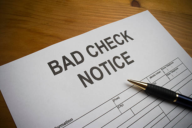 Bad Check Notice Form to fill out for a Bad Check received. Form is on a wooden desk with a pen as a prop. insufficient funds stock pictures, royalty-free photos & images