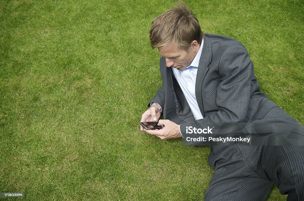 Empresario controles Smartphone on Green Grass - Foto de stock de Actividad de fin de semana libre de derechos