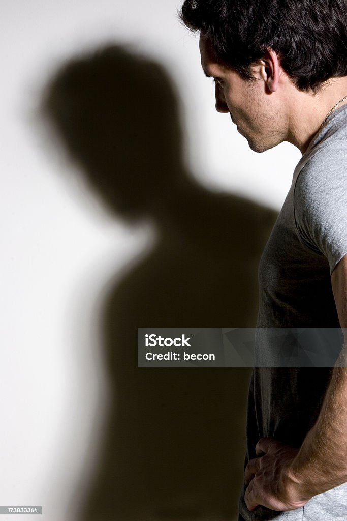 Troubled Past Man looking at his shadow. Some grain in shadow. Adult Stock Photo