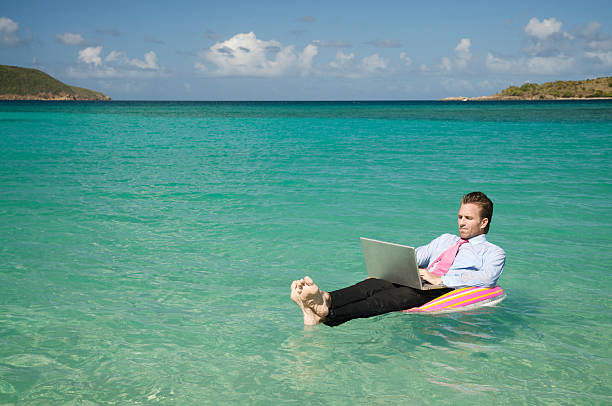 Photo of Businessman Floating Outdoors in Tropical Sea Working on Laptop