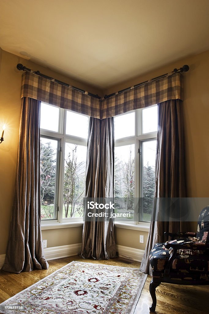 Wrought iron drapery Corner window coverings using a wrought iron rod and puddled side panels Chair Stock Photo