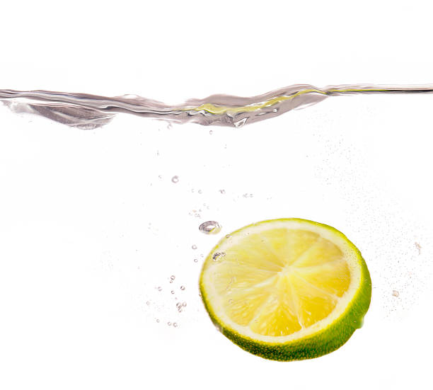 istock slice of lime dropping into water 173835043