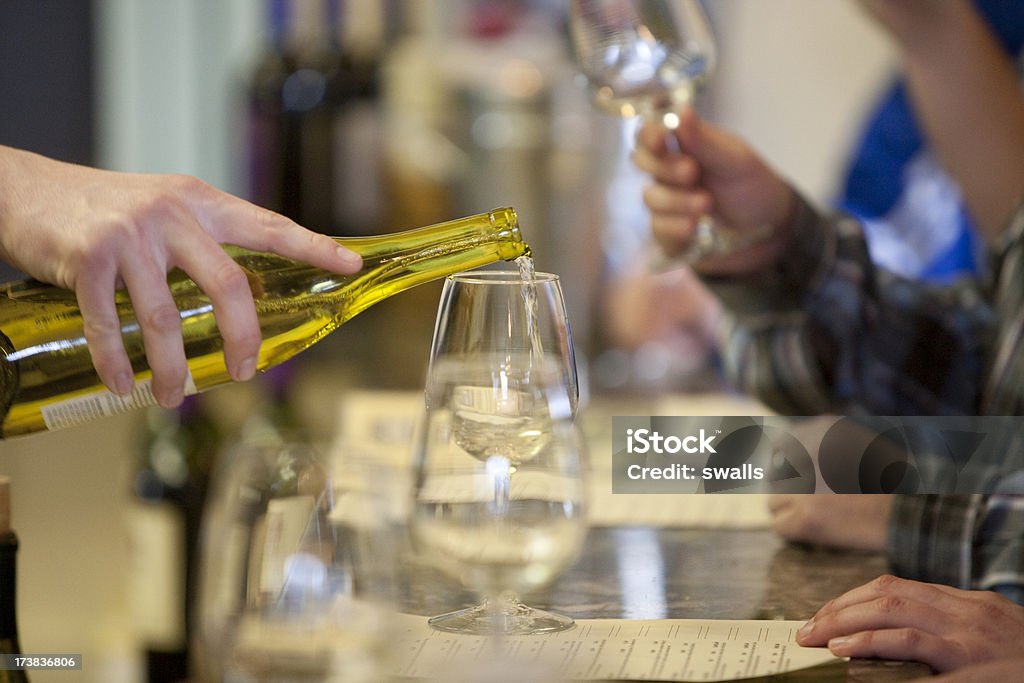 White Wine Pour A female hand pouring a glass of white wine in a wine tasting room. Alcohol - Drink Stock Photo