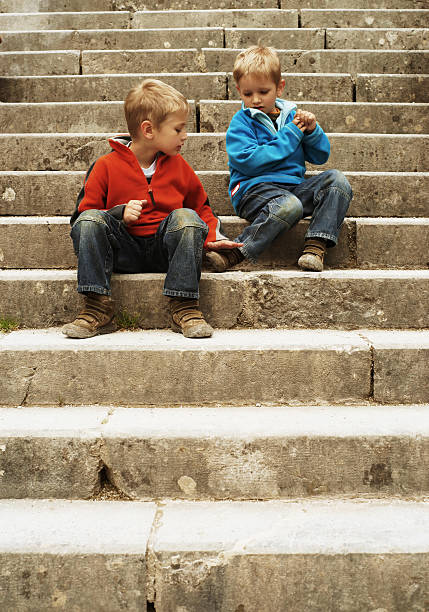 Happy little boys playing cards on a small wall. They don't mind they will skip some classes if they play too long.