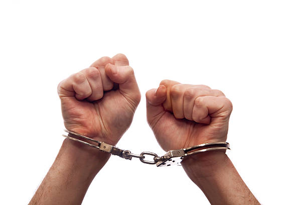 Handcuffed hands making a fist stock photo
