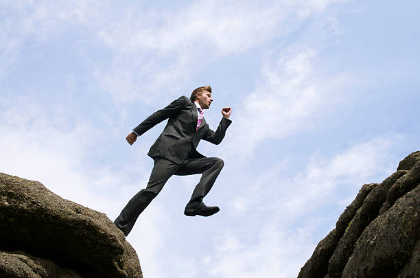 istock Courageous Businessman Jumping Over Rock Chasm 173840658