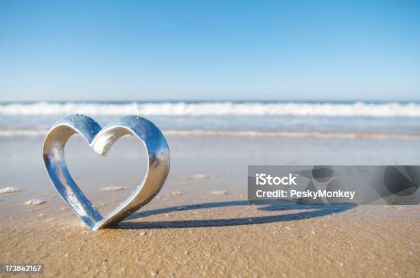 Romantic Honeymoon Silver Heart On Beach In Sand With Waves Stock Photo - Download Image Now