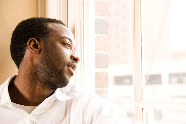 istock Young African American Male looking out window 173844909