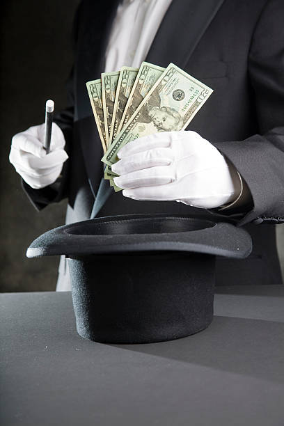 Magician man pulling money from hat The magician makes money appear from his hat.  magician money stock pictures, royalty-free photos & images