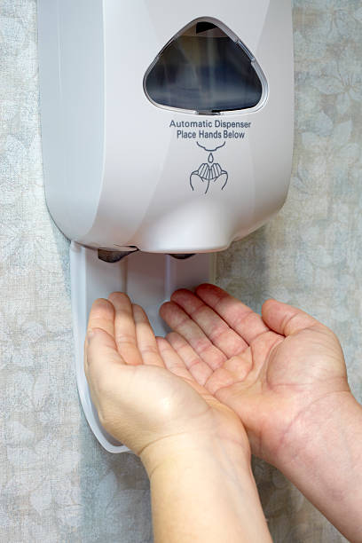 Hand Sanitizer Dispenser and Two Female Hands stock photo