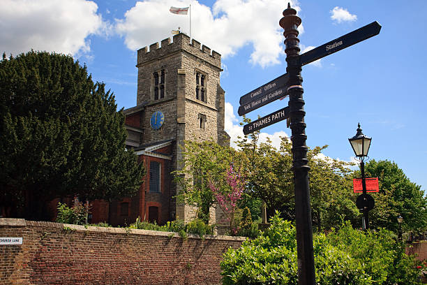 English village church and signpost Saint Mary's Church, Twickenham, UK with Saint George's flag flying marys stock pictures, royalty-free photos & images