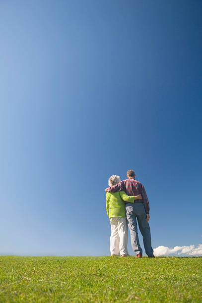 Embraced couple looking at the blue sky stock photo