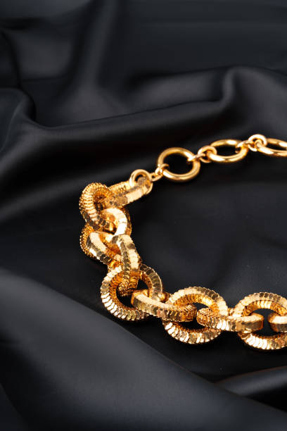 istock Gold chain on black silk fabric background 1738468432