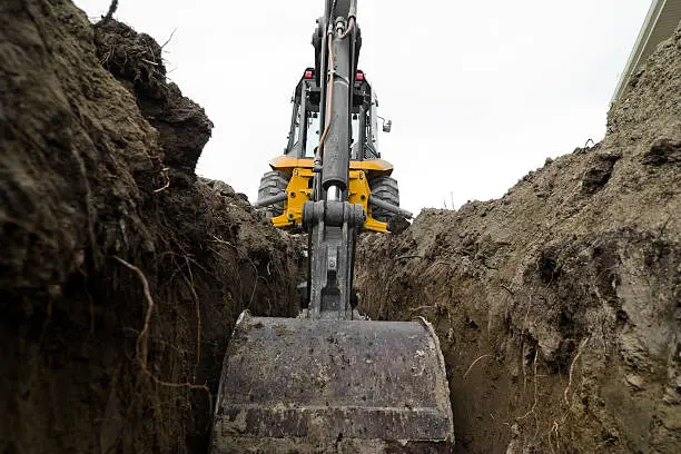 A backhoe digging a trench for some electrical/plumbing lines.