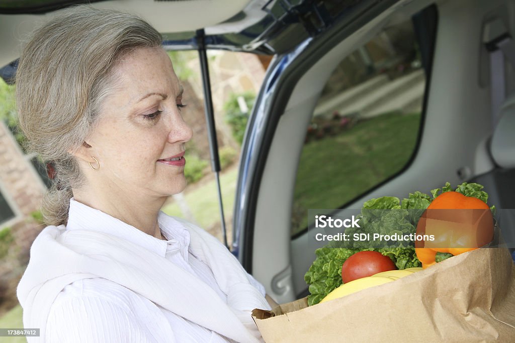 Femme âgée tenant des légumes épicerie dans Coffre de voiture - Photo de Adulte libre de droits