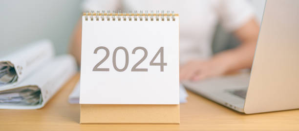 istock 2024 Year Calendar on table with business woman using laptop computer. countdown, Happy New Year, Resolution, Goals, Plan,  Action, Mission and financial Concept 1738474390