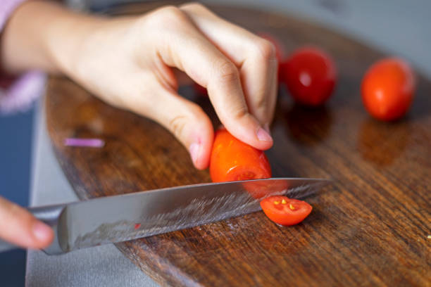 istock child's hand cuts a cherry tomato into slices on a cutting board 1738475387
